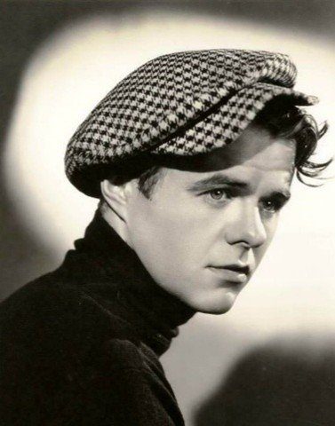 Black and white portrait of a young Elisha Cook Jr. in a checked cap